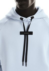 Light blue hoodie with a smooth texture, featuring a black drawstring and a rectangular black label with "SWISS ENGINEERING" text.