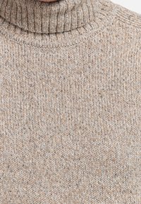 Béžový pletený rolák s texturovaným vzorem, s žebrovaným límcem a měkkou středně těžkou látkou. Výrazný melírovaný efekt.