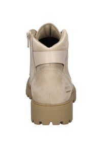 Beżowe zamszowe botki za kostkę z beżowym elastycznym paskiem przy pięcie, robustną brązową podeszwą oraz wyściełanym kołnierzem dla komfortu. Zamek błyskawiczny po boku.