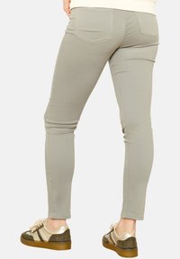Slim-fit, svetlosivi hlače z gladko teksturo, z dvema zadnjima žepoma in srednjim pasom, v kombinaciji s športnimi večbarvnimi supergami.