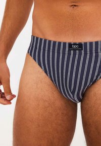 Slip da bagno a righe blu navy realizzati in un tessuto morbido, con etichetta logo sulla vita e un design aderente.