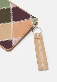 Pochette zip multicolore in verde, beige, bordeaux e rosa con cuciture in contrasto; presenta una tracolla staccabile in tono e accessori in argento.