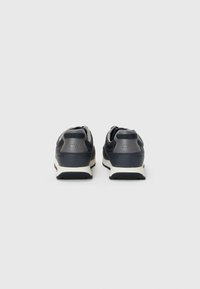Dark grey athletic shoes with a smooth leather upper, padded collar, perforated accents, and a white midsole. Simple and functional design.