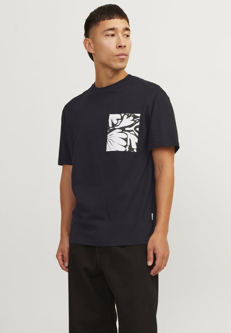 Marineblå bomuldst-shirt med et hvidt blomstret lomme-design, rund halsudskæring og korte ærmer, med en afslappet pasform og minimal branding.