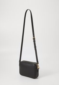 Sac bandoulière noir en cuir lisse, de forme rectangulaire avec une fermeture éclair, une sangle ajustable et des accents en métal doré.