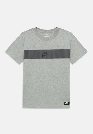 Harmaa puuvillainen t-paita, jossa on musta vaakasuora raita, jossa on Nike-logo. Pyöreä kaula-aukko, lyhyet hihat ja etiketti alareunassa kulmassa.