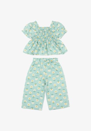 Ensemble deux pièces vert menthe avec des manches courtes bouffantes et un pantalon à jambes larges, décoré d'un motif floral de marguerites blanches et jaunes.