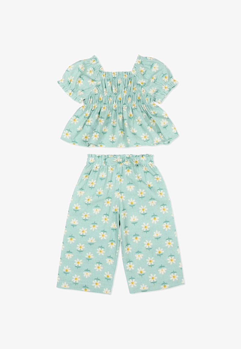 Mintgroene tweedelige outfit met korte pofmouwen en wijde broekspijpen, versierd met een witte en gele madeliefjesbloemenprint.