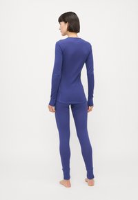 Lilla langermet topp og matchende leggings laget av myk stoff, med en tettsittende design og ribbede mansjetter.