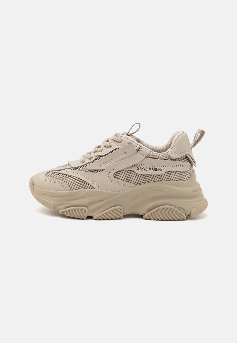 Zapatilla beige con una mezcla de cuero suave y malla. Suela gruesa con tracción texturizada. Presenta cordones finos y una lengüeta en el talón.