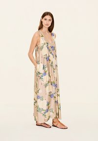 Blumenkleider in hellbeige mit blauen und weißen Blumen. Ärmelloses Design mit lockerem Schnitt und Taschen, aus glattem Stoff gefertigt.