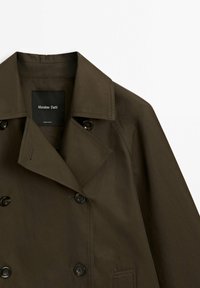 Trench-coat vert olive foncé à double boutonnage avec un large col et des boutons noirs, marque Massimo Dutti, fabriqué au Vietnam.