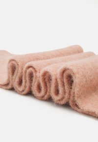Tessuto di feltro rosa piegato in strati morbidi e ondulati, che mostra una superficie texturizzata con una leggera lucentezza e sottili variazioni di colore.