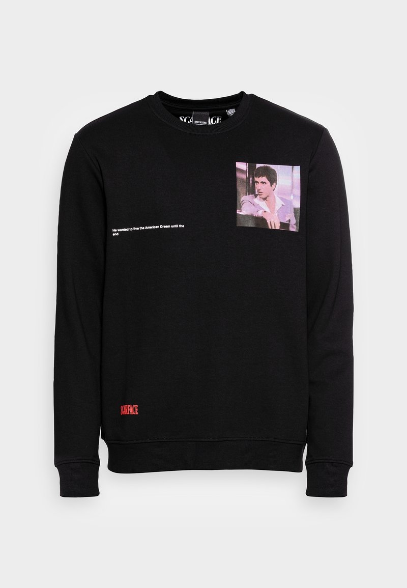 Sweat-shirt noir à manches longues avec une petite photo d’un homme en veste rose sur la poitrine et un texte blanc indiquant « Il voulait vivre le rêve américain jusqu’à la fin. »