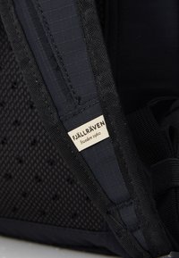 Dunkelblauer Stoff-Rucksack mit Mesh-Details, stabilen Trägern und einem Etikett mit der Aufschrift "FJÄLLRÄVEN Schweden 1960" in Schwarz und Weiß.