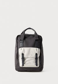Black fabric backpack with a cream front pocket, featuring two adjustable blue straps and a discreet logo. Structured design with a top handle.