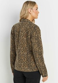 Denimjacka med leopardmönster, krage, knappstängning och långa ärmar; med en strukturerad tyg i nyanser av brunt och svart.