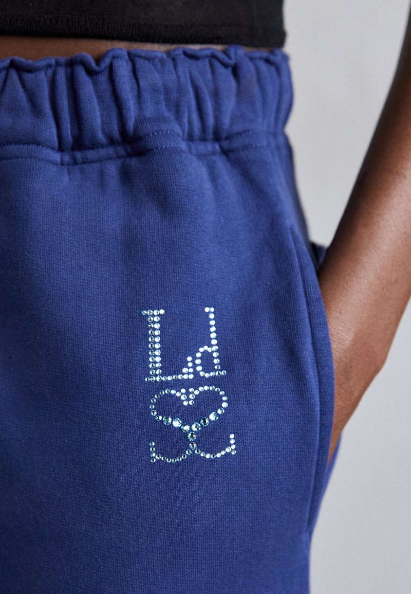 Blaue Sweatpants mit einem gerafften Bund und einem Strassdesign, das "Ld" und ein Herz zeigt, aus einem weichen Stoffmaterial.