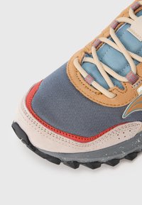 Többszínű sneaker szürke hálós felsőrésszel, világoskék kiegészítőkkel, világosbarna bőrbetétekkel, piros részletekkel, krémszínű fűzőkkel és struktúrált fekete talppal.