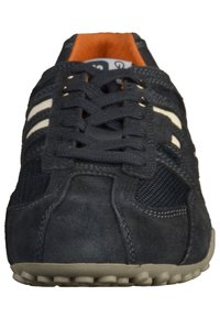 Navy blue athletic shoe with gray suede and mesh. Features white stripes, round lacing, and a textured rubber sole with small studs.