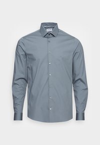 Camicia button-up grigia chiara realizzata in un tessuto morbido. Presenta un colletto classico e maniche lunghe. Include un piccolo logo sul petto.