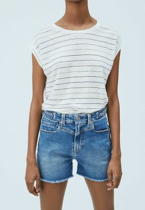 Personne portant une chemise blanche à manches courtes avec de fines rayures horizontales et un short en denim bleu taille haute avec des bords effilochés.