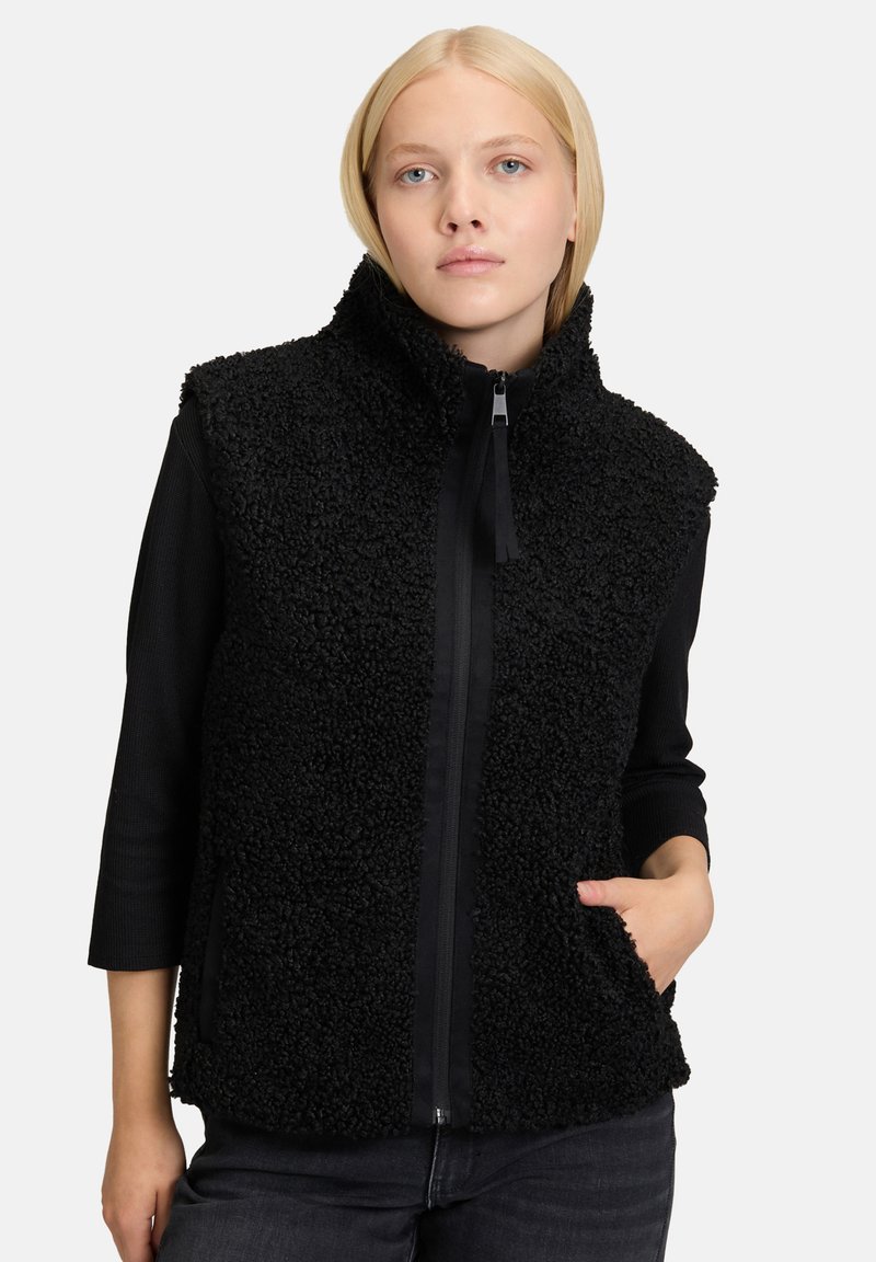 Czarna polarowa kamizelka z wysokim kołnierzem, zapinana na zamek z przodu, z bocznymi kieszeniami. Tekstura jest puszysta z gładkim czarnym wykończeniem.
