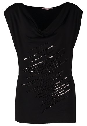 Femme portant un haut noir sans manches à sequins, un jean skinny bleu, des talons hauts noirs, tenant une petite pochette argentée rectangulaire.