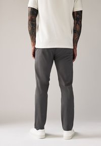 Gray trousers made of lightweight fabric, featuring a straight cut and slight stretch. Paired with white sneakers, smooth texture.