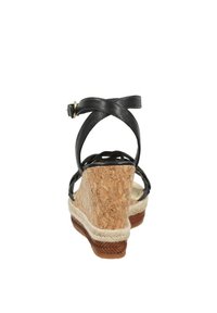 Sandalias de cuña de cuero negro con base de corcho y ribete de yute trenzado. Presenta una correa en el tobillo ajustable y un diseño abierto para ventilación.