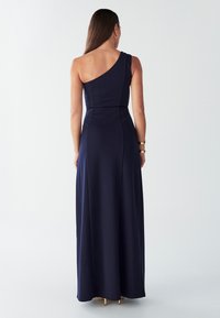 Tumesinine, ühe õlaga kleit, millel on keha järgiv ülakehaosa, voolav maksiseelik ja sile tekstuur, puhta ja minimalistliku disainiga.