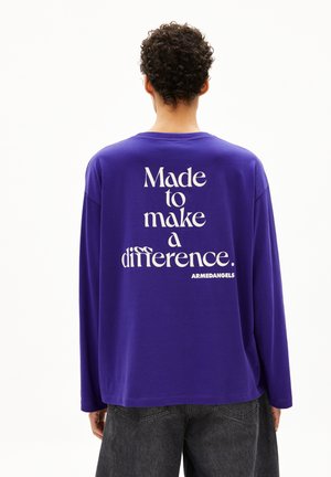 Lila Langarm-T-Shirt mit weißem Text auf dem Rücken, der lautet: "Gemacht, um einen Unterschied zu machen. ARMADANGETS." Einfaches Rundhalsdesign.