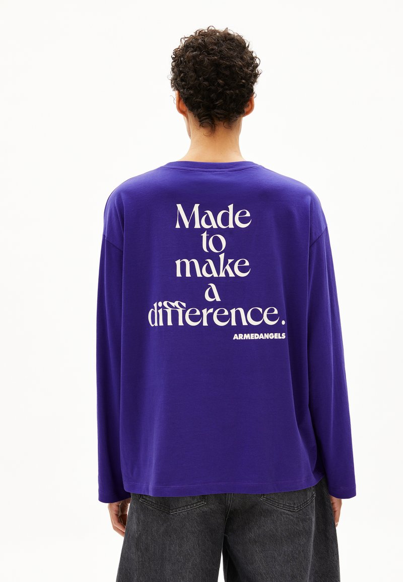 Lila Langarm-T-Shirt mit weißem Text auf dem Rücken, der lautet: "Gemacht, um einen Unterschied zu machen. ARMADANGETS." Einfaches Rundhalsdesign.