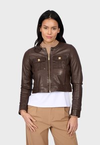 Giacca cropped in pelle marrone con collo rotondo, chiusura zip frontale, due tasche sul petto e dettagli con bottoni dorati. Tessuto liscio.