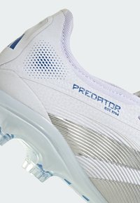 White athletic shoe with textured upper, blue accents, and metallic silver detailing. Notable perforations and translucent outsole.