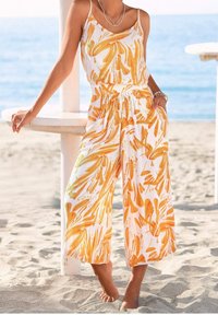 Combinaison blanche avec des motifs abstraits orange vif, dotée de fines bretelles, d'une taille cintrée et de jambes larges et fluides. Tissu texturé.