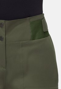 Gröna högmidjade shorts med en slät yta, knappstängning och en sidficka med en kontrasterande grön elastisk panel.