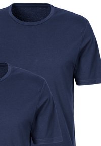 Granatowe koszulki z krótkim rękawem wykonane z bawełny, z okrągłym dekoltem. Charakteryzują się miękką fakturą i prostymi wykończeniami, ułożone w stosie na zdjęciu.