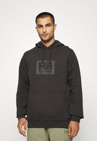 Hoodie noir en mélange de coton, avec une poche avant et une capuche à cordon. Logo texturé imprimé sur la poitrine en gris. Design simple.