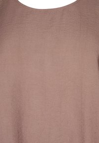 Light mauve top with a soft, textured fabric. Features a wide neckline and a loose, flowing design.