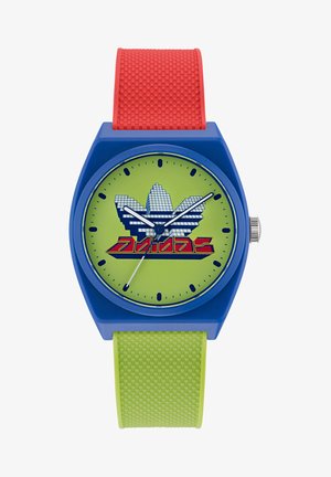 Barevné hodinky s modrým pouzdrem, zeleným ciferníkem a kontrastními červenými a zelenými řemínky. Obsahují logo Adidas v pixelovém stylu.