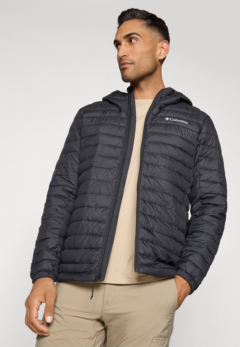 Chaqueta negra acolchada con capucha, cierre de cremallera y logo de Columbia en el lado izquierdo del pecho. Presenta puños acanalados y paneles acolchados horizontales.