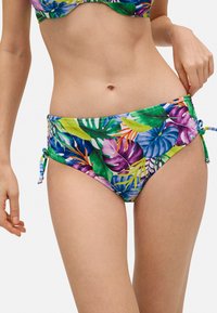 Una parte de abajo de bikini con un vibrante patrón de hojas tropicales en verde, púrpura y amarillo. Presenta lazos a los lados y una textura de tela suave.