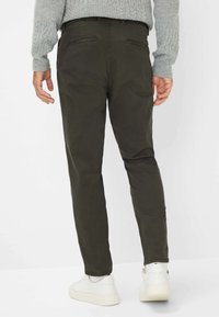 Slimfit donkergroene broek van een katoenmix. Beschikt over achterzakken en een soepele textuur, gecombineerd met witte sneakers.