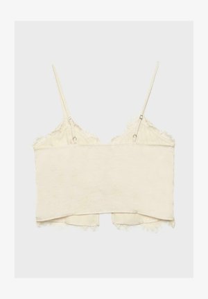 Camisole corta color crema con spalline sottili regolabili e bordatura in pizzo lungo i bordi, mostrata distesa su uno sfondo neutro.