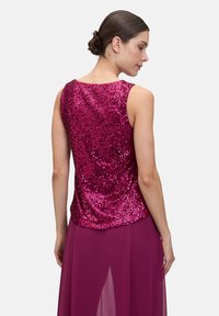 Fuchsia pailletten top met een ronde halslijn en mouwloos ontwerp, gecombineerd met een vloeiende, semi-doorzichtige rok in een bijpassende tint.