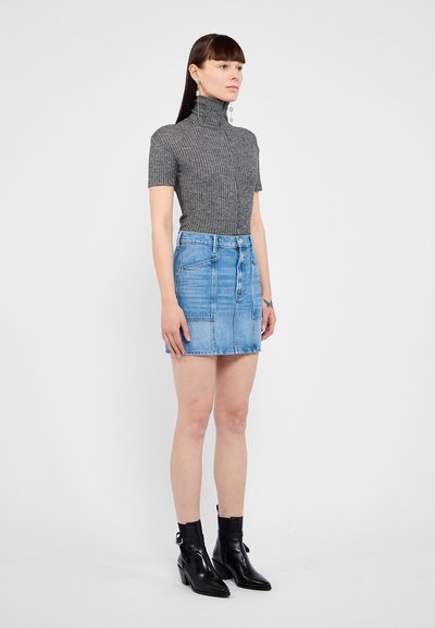 Pilka raukšlėta turtlenkio viršūnė derinama su šviesiai mėlyna džinsine mini sijonu. Modelis užsidėjęs juodas aulinukus su smailiu pirštu ir blokuotu kulnu.