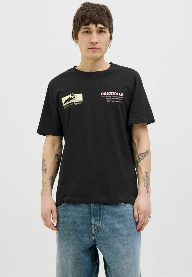 Zwarte katoenen t-shirt met grafische prints aan de voorkant in witte en roze tekst. Korte mouwen en een relaxte pasvorm, gecombineerd met lichtblauwe denim jeans.