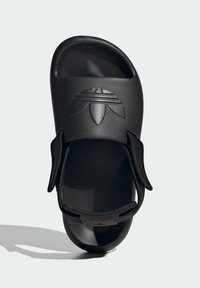 Black slide sandal made from smooth synthetic material, featuring a textured upper with a logo and adjustable strap for secure fit.