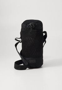 Borsa nera in rete con forma cilindrica, dotata di tracolla regolabile, chiusura a cordoncino e una patch con logo sulla base.